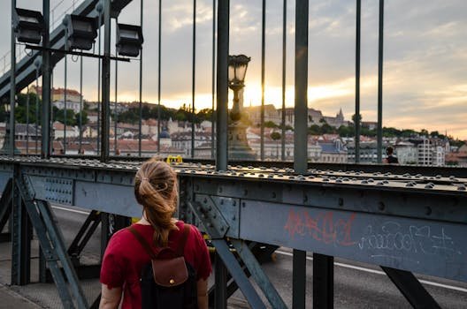 The Best Relocation Checklist for Moving to Budapest in 2025 A person on a bridge in Budapest watching the sunset over the historic city skyline.