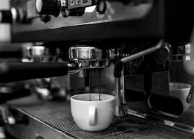 Top 10 Hidden Gems in Budapest Only Locals Know Monochrome close-up of an espresso machine pouring coffee into a cup.