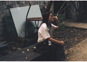 Top 10 Hidden Gems in Budapest Only Locals Know A woman in sunglasses and white t-shirt sits on a wooden bench outdoors.