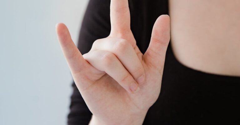 Close-up of a woman making a sign language gesture with her hand on a white background.